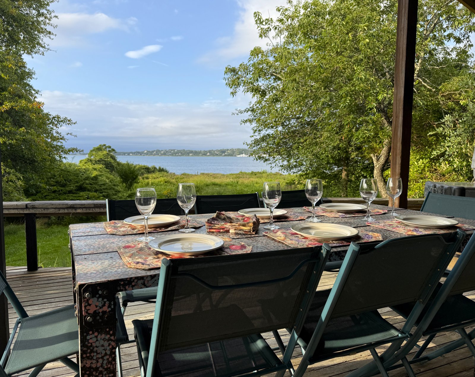 outdoor dining table on covered deck with lake in background