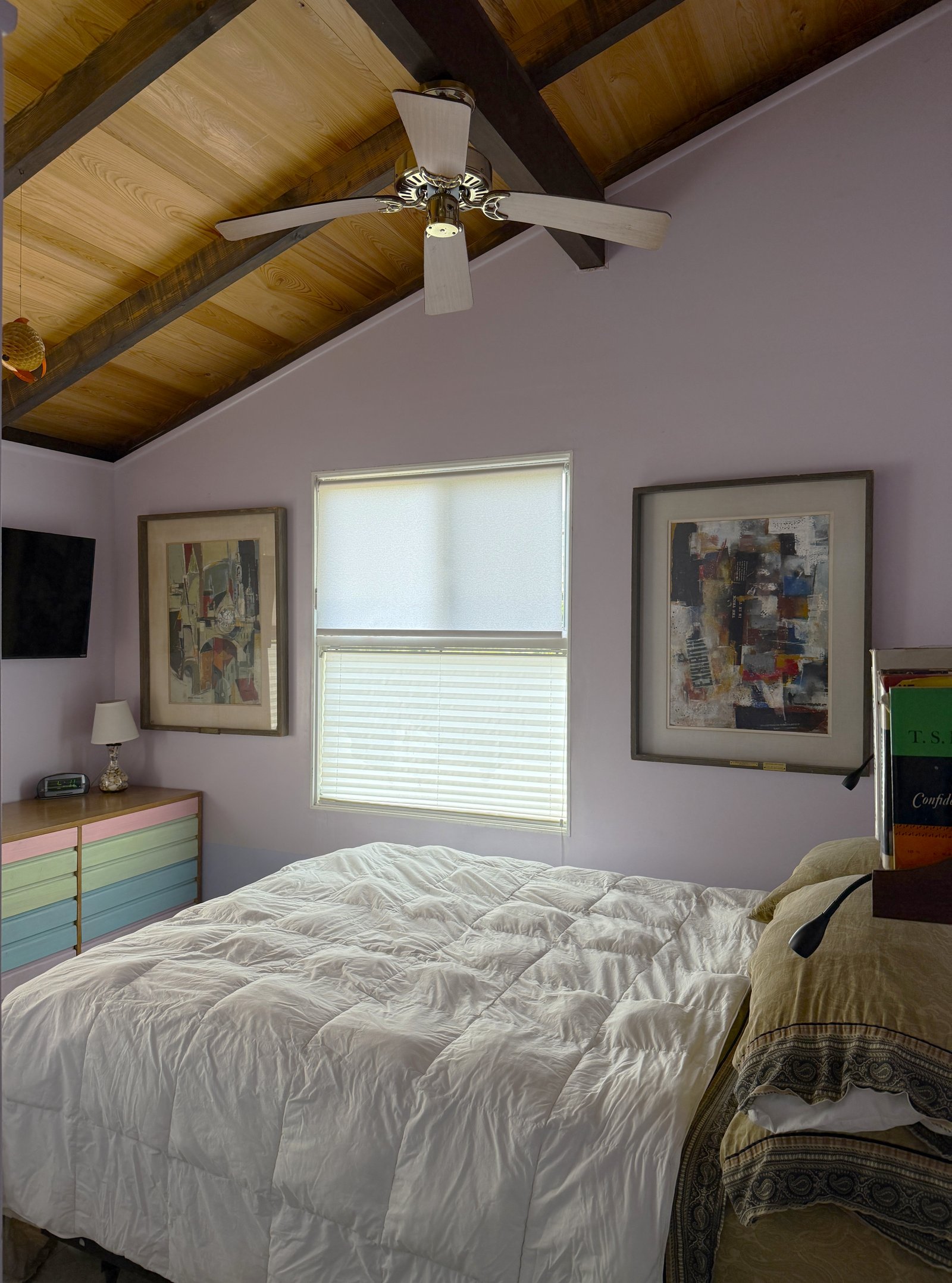middle bedroom showing bed, artwork, dresser, ceiling fan, cypress sloped ceiling