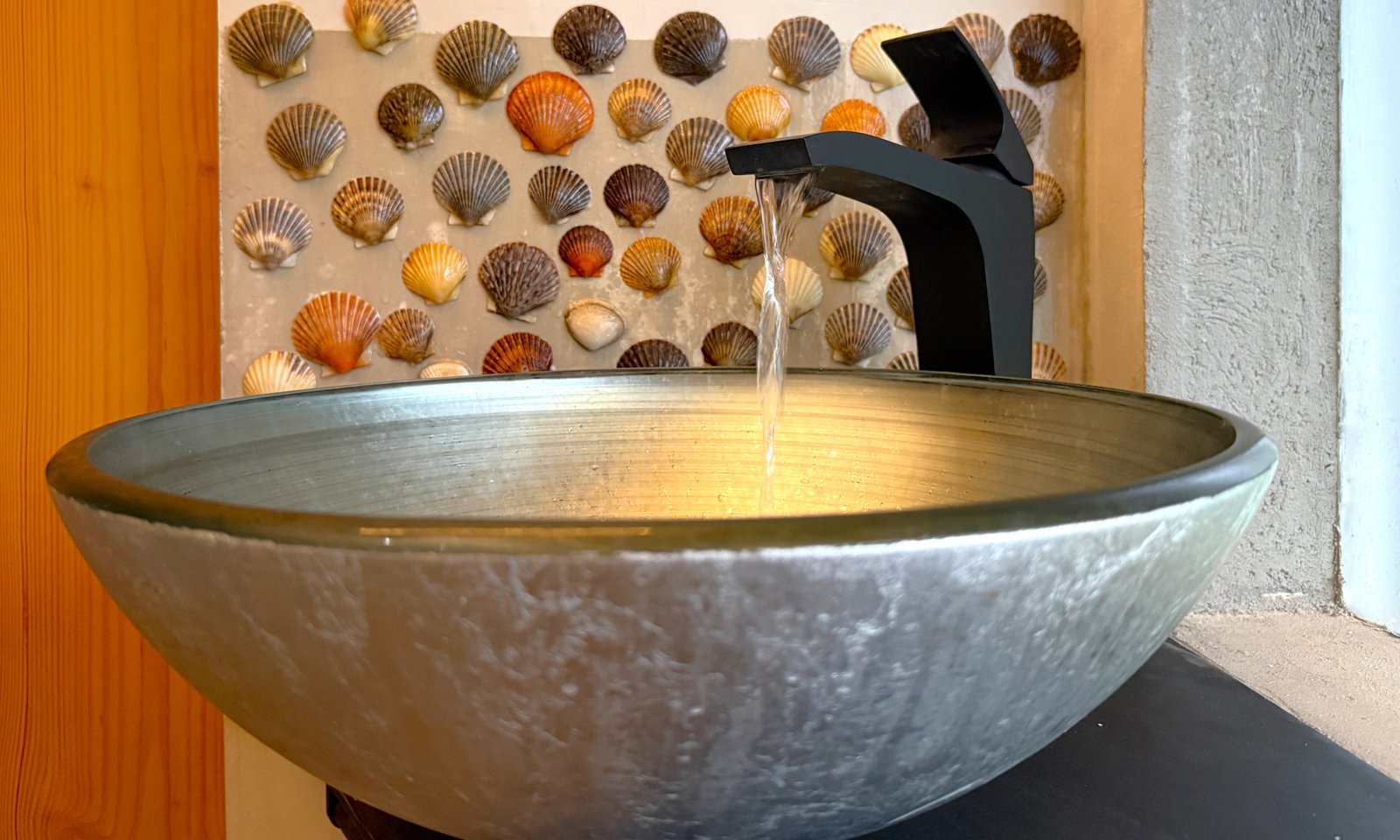 north bathroom basin vessel sink and faucet with wall of shells