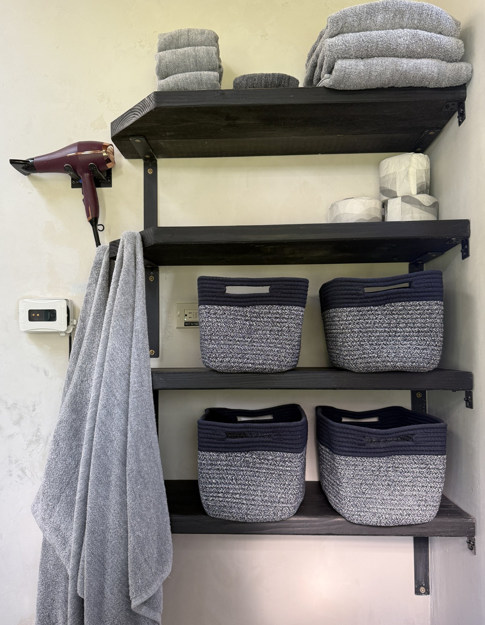 shelves with towels and storage bins, hanging towels, hair dryer in north bathroom