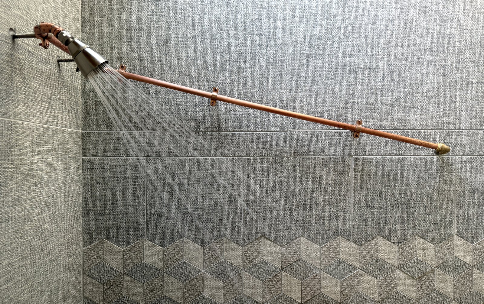 showerhead, exposed pipe, tilework in north bathroom